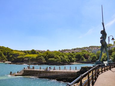 A waterfront walkway with a large sculpture of a woman holding a sword at The Coach House The Grove in Combe Martin