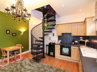 A kitchen with spiral staircase and dining table at The Coach House, The Grove in Combe Martin