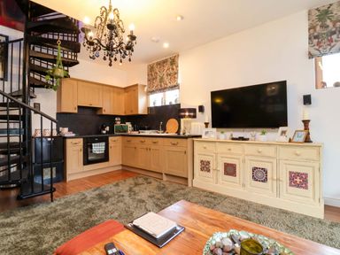 An open plan living room and kitchen with a spiral staircase at The Coach House, The Grove Combe Martin