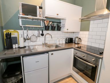A kitchen with a microwave oven sink utensils and white cabinets at Emerald Suite in Barmouth