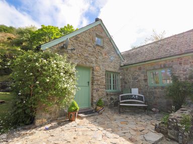 Stone house exterior with green door and windows a bench and some potted plants at Glyn Yr Efail Moylegrove nr Newport and Cardigan