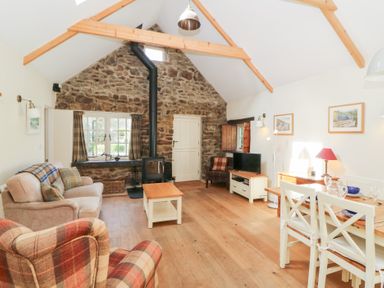 A living room with sofas a wood stove and a dining table at Glyn Yr Efail in Moylegrove nr Newport and Cardigan