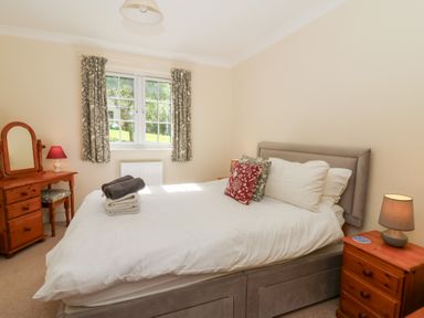 A bedroom with a double bed bedside tables with lamps a window with curtains and a dressing table at Glyn Yr Efail in Moylegrove nr Newport and Cardigan