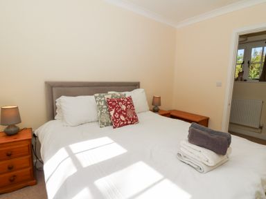 A bedroom with a double bed white bedding decorative pillows bedside tables with lamps and folded towels on the bed at Glyn Yr Efail in Moylegrove nr Newport and Cardigan