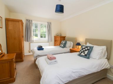 A bedroom with two single beds wooden furniture and a window with curtains at Glyn Yr Efail in Moylegrove nr Newport and Cardigan