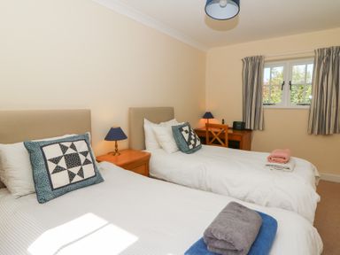 A bedroom with two single beds bedside table lamps a desk and window at Glyn Yr Efail in Moylegrove nr Newport and Cardigan