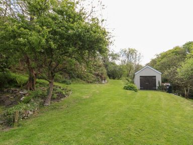 A grassy path leading to a small building surrounded by trees and bushes at Glyn Yr Efail Moylegrove nr Newport and Cardigan