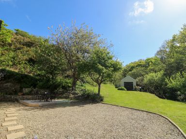 A garden with a gravel area and stepping stones a small shed and trees at Glyn Yr Efail in Moylegrove nr Newport and Cardigan