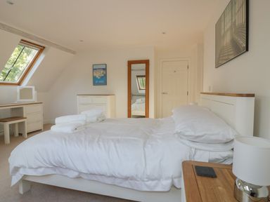 A bedroom with a bed folded towels wooden framed mirror chest of drawers and skylight window at Stores & Supplies in Bodmin