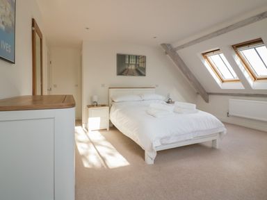 A bedroom with a double bed with white bedding two bedside tables and two skylight windows at Stores & Supplies in Bodmin