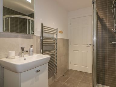A bathroom with a sink cabinet towel radiator and shower enclosure at Stores & Supplies in Bodmin