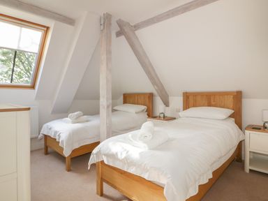 A bedroom with two single beds wooden bed frames white bedding and towels on beds at Stores & Supplies in Bodmin
