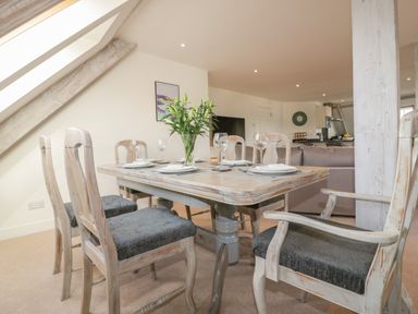 A dining table with six chairs and table settings in an open living area at Stores & Supplies in Bodmin