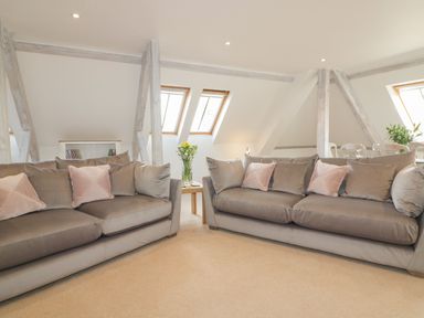 A living room with two gray sofas and pink pillows near windows at Stores & Supplies Bodmin