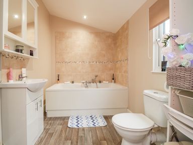 A bathroom with a bathtub sink and toilet and a window with a shelf unit at Sparrows Den Lodge in Winchelsea Beach