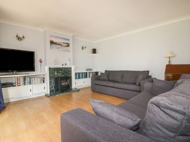 A living room with two grey sofas a television and a fireplace at Three Jays in Lanreath