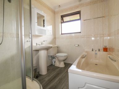 A bathroom with a shower, sink, toilet, bathtub, and a window at Three Jays in Lanreath