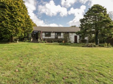 A single story house with large grass lawn and surrounding trees at Three Jays in Lanreath