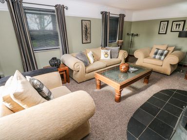 A living room with beige sofas a wooden coffee table and framed artwork on walls at Mountain Farm in Broad Haven