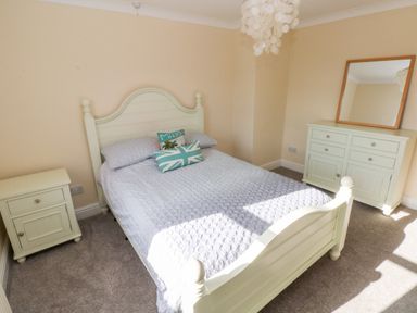 A bedroom with a bed with pillows a nightstand a dresser with a mirror and a ceiling light at Mountain Farm in Broad Haven
