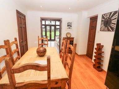 A dining room with a wooden table and chairs a wooden cabinet and a door leading outside at Mountain Farm in Broad Haven