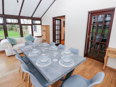 A dining area with a set dining table next to a white sofa and wooden cabinet at Mountain Farm in Broad Haven