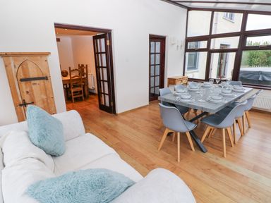 A dining area with a set table and gray chairs next to a white sofa with blue cushions at Mountain Farm in Broad Haven