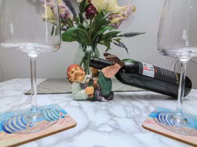 A dining table with wine glasses coasters and a figurine at Hidden Treasure Brixham