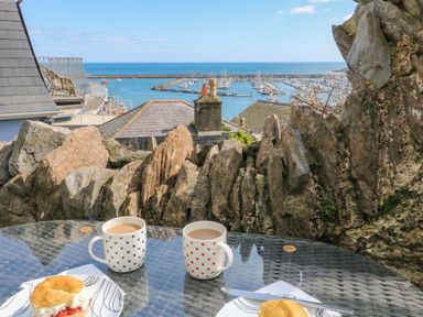 An outdoor scene with coffee cups and scones overlooking a marina at Hidden Treasure in Brixham