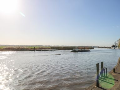 A river with a barge and grassy banks under a clear sky at Foundry Cottage in Reedham