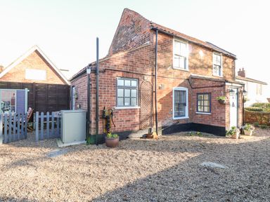 A brick house with multiple windows flower pots and a gravel yard at Foundry Cottage in Reedham