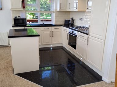 A kitchen with white cabinets black countertops a microwave oven and a gas stove at Lodge 11 in Tavistock