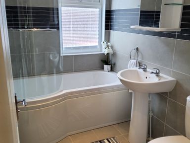 A bathroom with a bathtub sink toilet and a window with blinds at Lodge 11 in Tavistock
