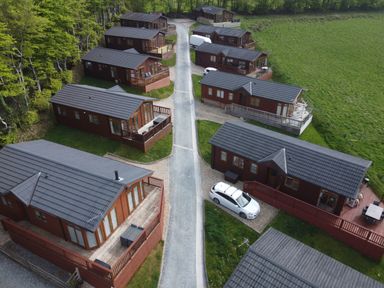 A cluster of wooden lodges with driveways in a rural setting at Lodge 11 Tavistock