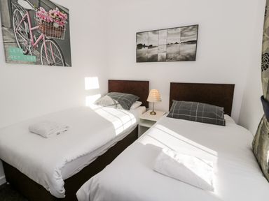 A bedroom with two single beds and a nightstand with a lamp at Halcyon in Moelfre near Benllech