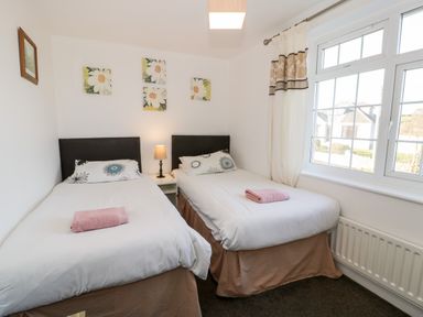A bedroom with two single beds and a window at Halcyon in Moelfre near Benllech