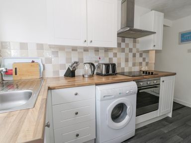 A kitchen with a sink knife set kettle toaster washing machine and oven at Halcyon Annexe Moelfre near Benllech