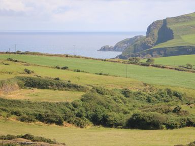 Green fields with bushes and a rocky hillside near the sea at Dooneen near Castletownshend County Cork