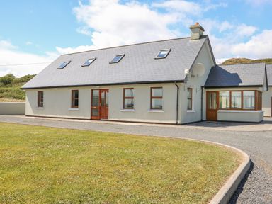 A single-story house with a pitched roof skylights multiple windows and a lawn at Dooneen near Castletownshend County Cork