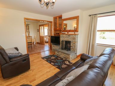 A living room with leather sofas stone fireplace and a television at Dooneen near Castletownshend County Cork