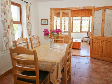 A dining room with a table and six chairs and a vase with flowers at Dooneen near Castletownshend County Cork