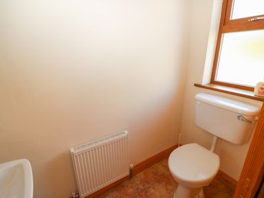 A small bathroom with a toilet a radiator and a window at Dooneen near Castletownshend County Cork