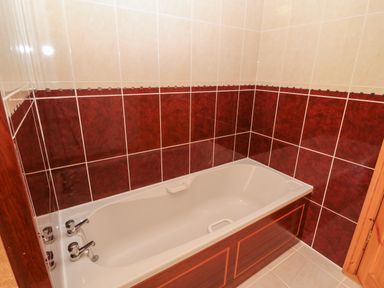 A bathroom with a built in bathtub and tiled walls at Dooneen near Castletownshend County Cork