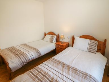 A bedroom with two single beds with striped bedding and a wooden nightstand with a lamp at Dooneen near Castletownshend County Cork