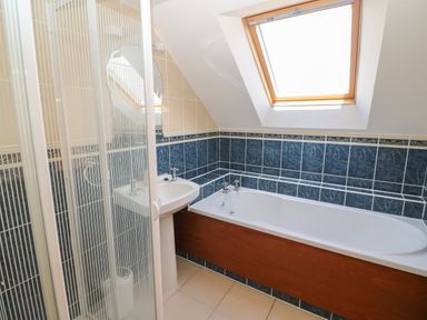 A bathroom with a bathtub a shower enclosure and a sink under a skylight at Dooneen near Castletownshend County Cork