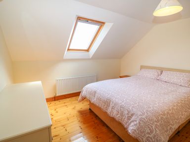 A bedroom with a double bed a skylight window a radiator a bedside table and a dresser at Dooneen near Castletownshend County Cork