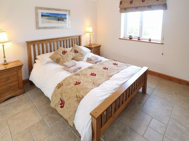 A bedroom with a wooden double bed and two bedside tables with lamps at Bryn Eiddon in Aberdaron
