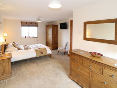 A bedroom with a bed desk chair wardrobe and mirror at Bryn Eiddon in Aberdaron
