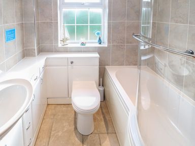 A bathroom with a toilet sink bathtub and storage cabinets at Bryn Eiddon in Aberdaron