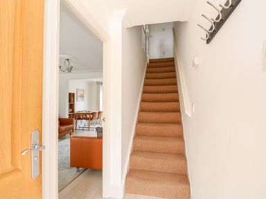 A carpeted staircase next to an open door leading to a room with brown chairs and a dining table at 5 Styleman Road Hunstanton